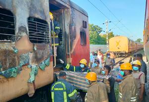 Firefighters hold a stretcher to carry bodies from a train coach where fire erupted in Madurai, in the southern Indian state of Tamil Nadu, Satursday, Aug. 26, 2023. A gas cylinder smuggled in by some passengers caused the fire killing nine people, according to a statement by the Southern Railway. (AP Photo)