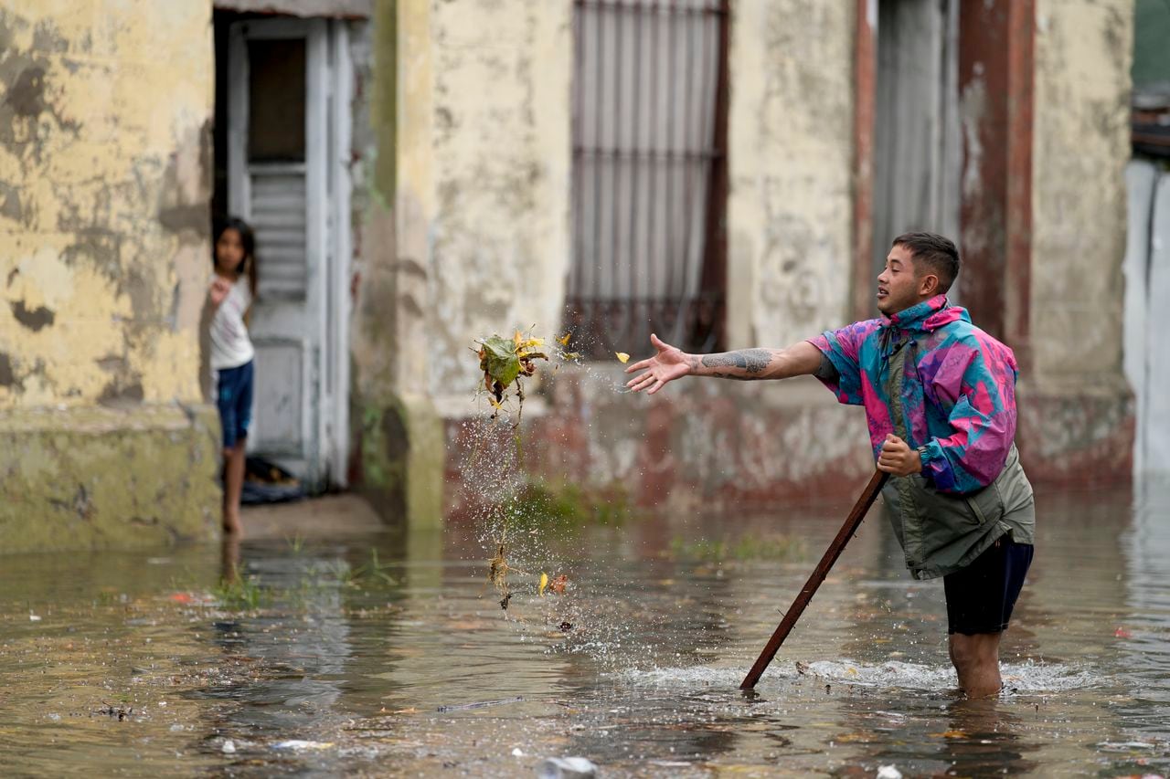 Un residente intenta desatascar un desagüe en una calle inundada después de fuertes lluvias en Avellaneda, en las afueras de Buenos Aires, Argentina, el martes 12 de marzo de 2024. (Foto AP/Natacha Pisarenko)