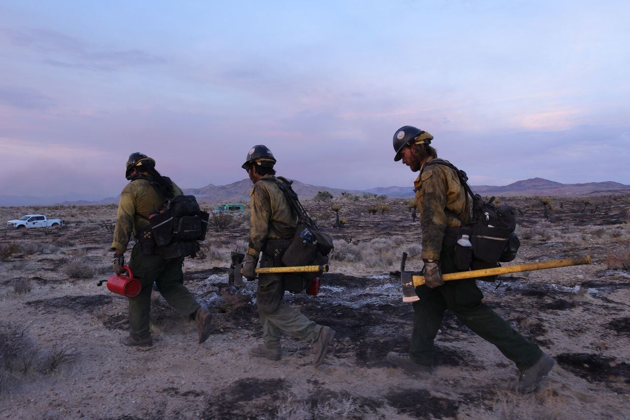 Los bomberos de Crane Valley Hotshot caminan mientras la reserva nacional arde.