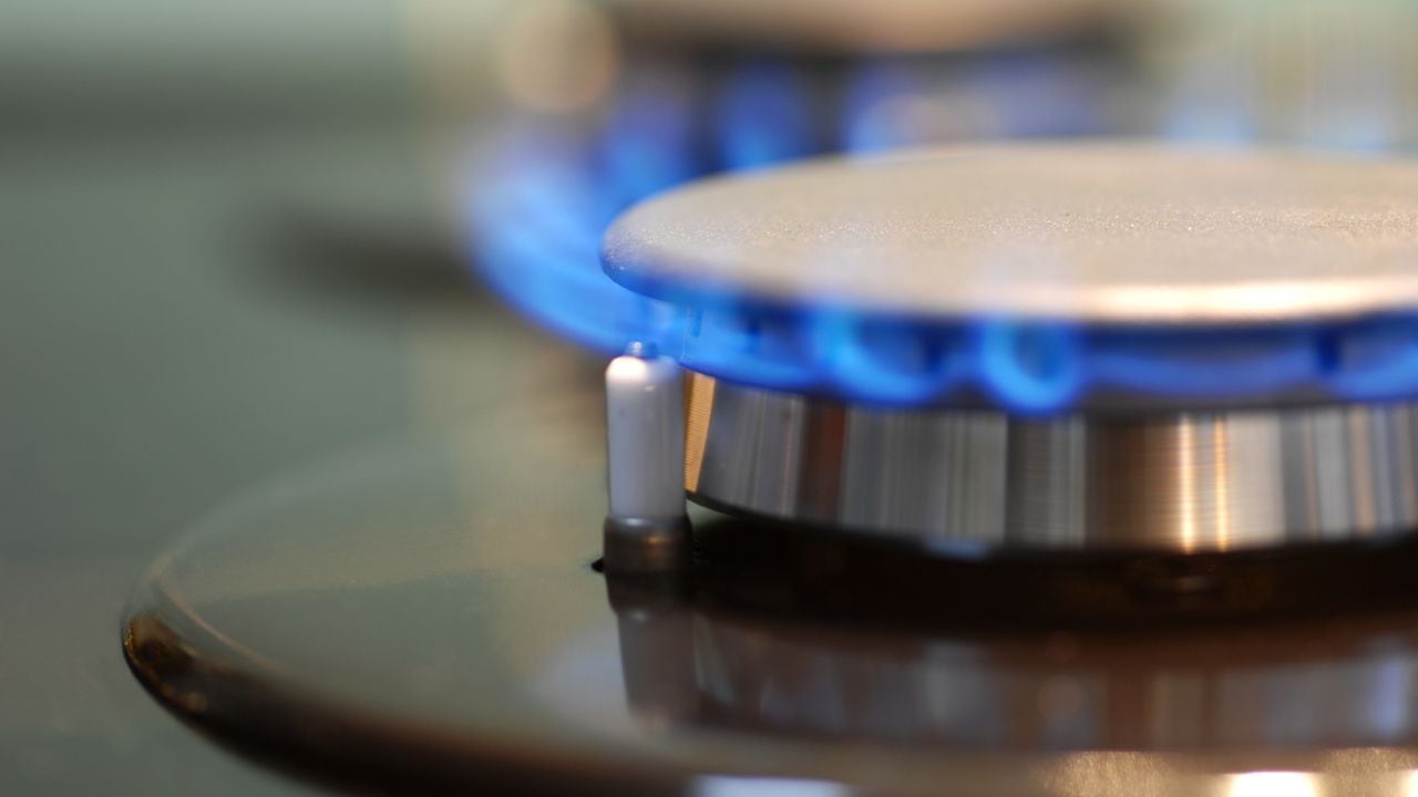 Imagen macro de encimera de gas en plena llama. Concéntrese en el frente del quemador y el encendedor a la izquierda de la llama.