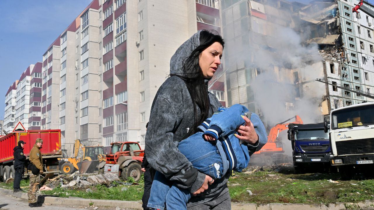 Una mujer pasa junto a edificios residenciales dañados mientras lleva a un niño en Uman, a unos 215 km al sur de Kiev. Foto: AFP