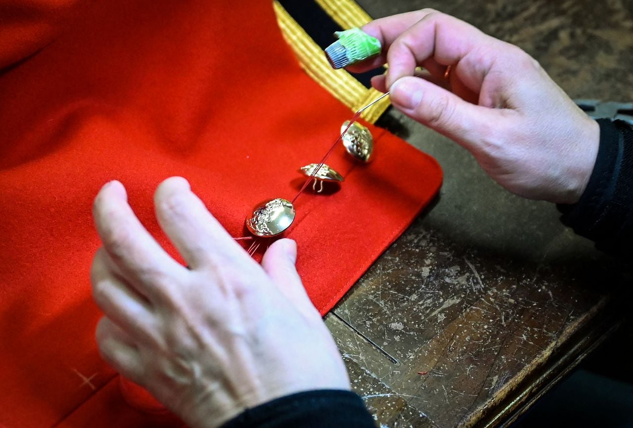 Un sastre cose botones en una túnica de salvavidas del rey que se usará durante la coronación del rey Carlos III de Gran Bretaña y su esposa Camilla, reina consorte de Gran Bretaña.