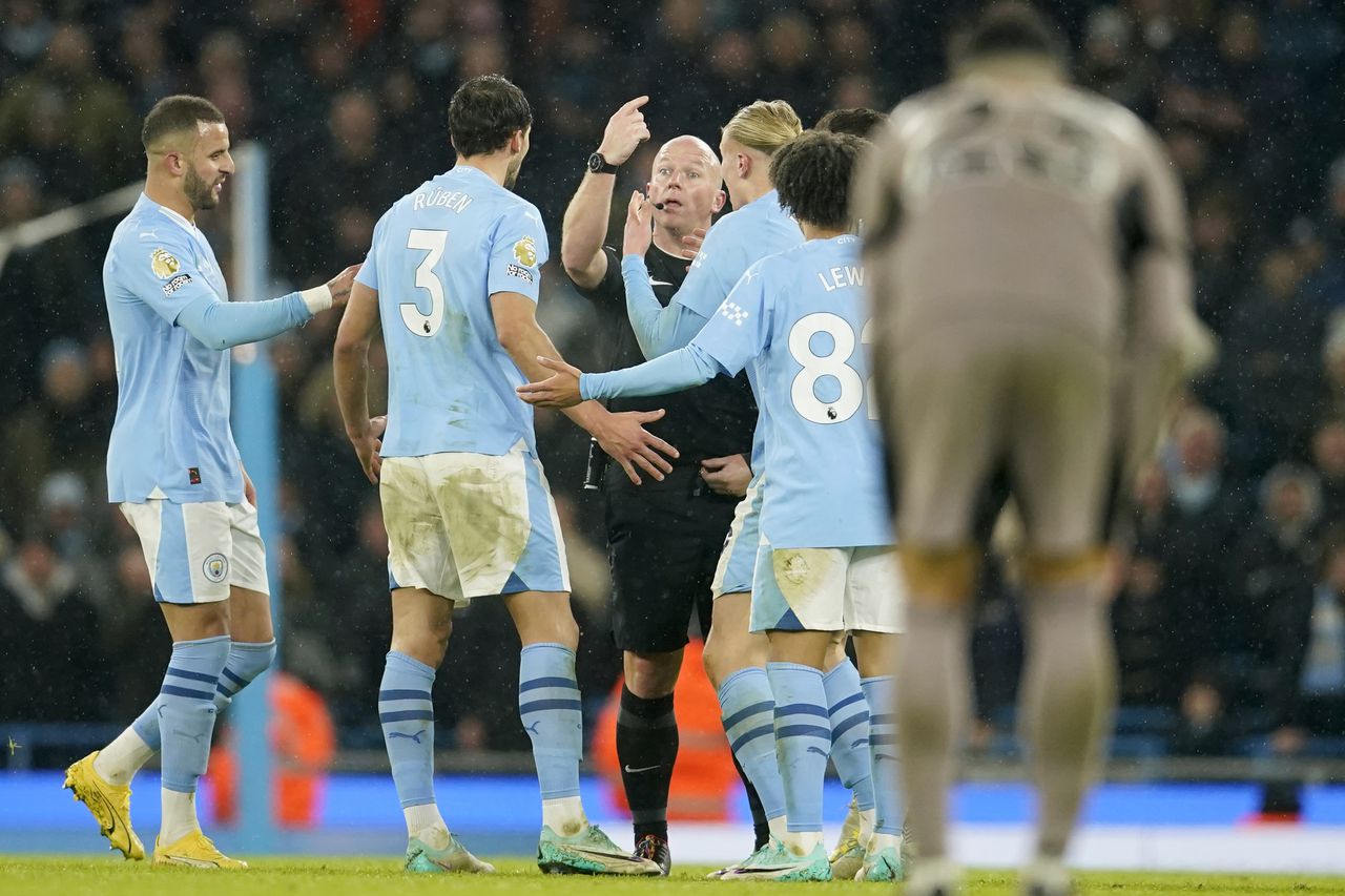Los jugadores del Manchester City rodean al árbitro Simon Hooper al final del partido contra Tottenham en la Liga Premier, el domingo 3 de diciembre de 2023, en Manchester. (AP Foto/Dave Thompson)