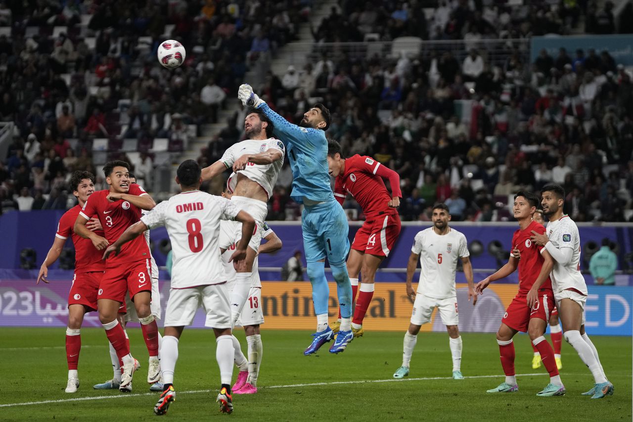 El portero iraní Ali Reza Safarbeiranvand, centro, alcanza el balón para salvar durante el partido de fútbol del Grupo C de la Copa Asiática entre Hong Kong e Irán en el Estadio Internacional Khalifa en Doha, Qatar, el viernes 19 de enero de 2024. (Foto AP/ Thanassis Stavrakis)
