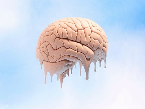 Side view of human brain model in mid air on blue sky background melting from the bottom