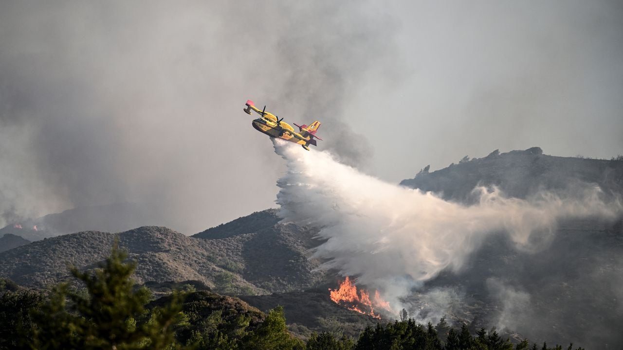 Un avión de extinción de incendios lanza agua sobre un incendio forestal cerca de la aldea de Vati en la parte sur de la isla griega de Rodas, a unos 70 km al suroeste de la ciudad capital el 25 de julio de 2023. (Imagen de referencia)
