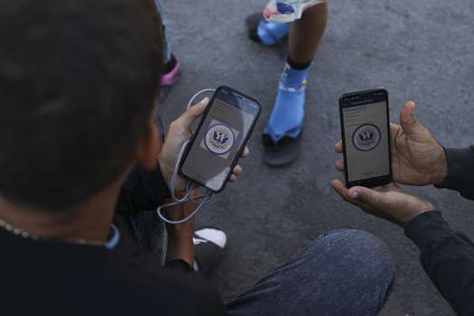 Migrantes venezolanos navegan por la aplicación móvil CBP One en busca de una cita para ingresar a Estados Unidos fuera de la estancia temporal del Instituto Nacional de Migración (INM) en Ciudad Juárez, estado de Chihuahua, México
