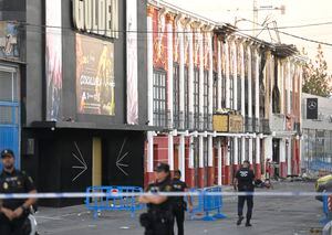 This picture taken on October 2, 2023 shows police officers blocking access after a fire in a nightclub that at least killed thirteen people at a nightclub in Murcia. At least 13 people were killed in a fire in a Spanish nightclub on October 1 in the morning, authorities said, with fears the toll could still rise as rescue workers sift through the debris. The fire appears to have broken out in a building housing the "Teatre" and "Fonda Milagros" clubs in the city of Murcia in southeastern Spain in the early morning hours. (Photo by JOSE JORDAN / AFP)