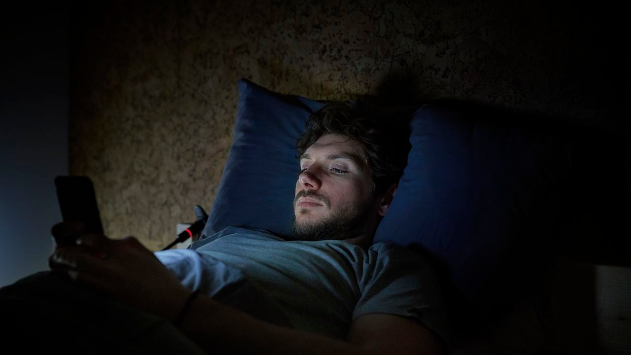 Hombre en la cama manipula su celular