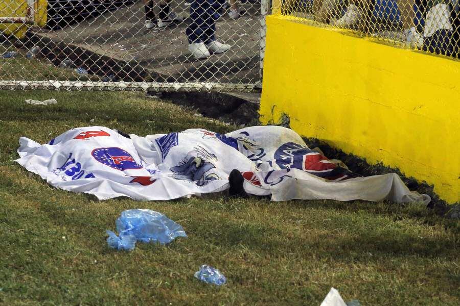 Los cuerpos de las víctimas se ven cubiertos con las banderas de Alianza luego de una estampida durante un partido de fútbol entre Alianza y FAS en el estadio Cuscatlán en San Salvador.