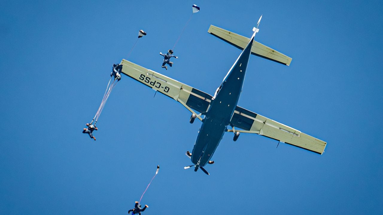Los paracaídas se despliegan después de la caída libre debajo de un avión Cessna