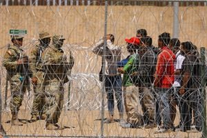 Los migrantes se paran cerca del muro fronterizo después de haber cruzado la frontera entre Estados Unidos y México para entregarse a los agentes de la Patrulla Fronteriza de los Estados Unidos mientras el ejército de los Estados Unidos hace guardia para inhibir el cruce de migrantes, visto desde Ciudad Juárez, México, el 11 de mayo de 2023.