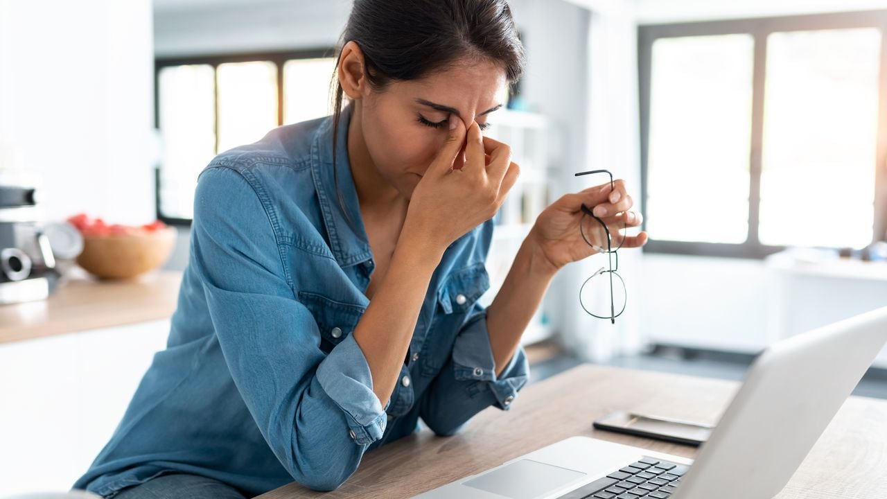 Foto de mujer de negocios estresada que trabaja desde casa en una computadora portátil con aspecto preocupado, cansado y abrumado.