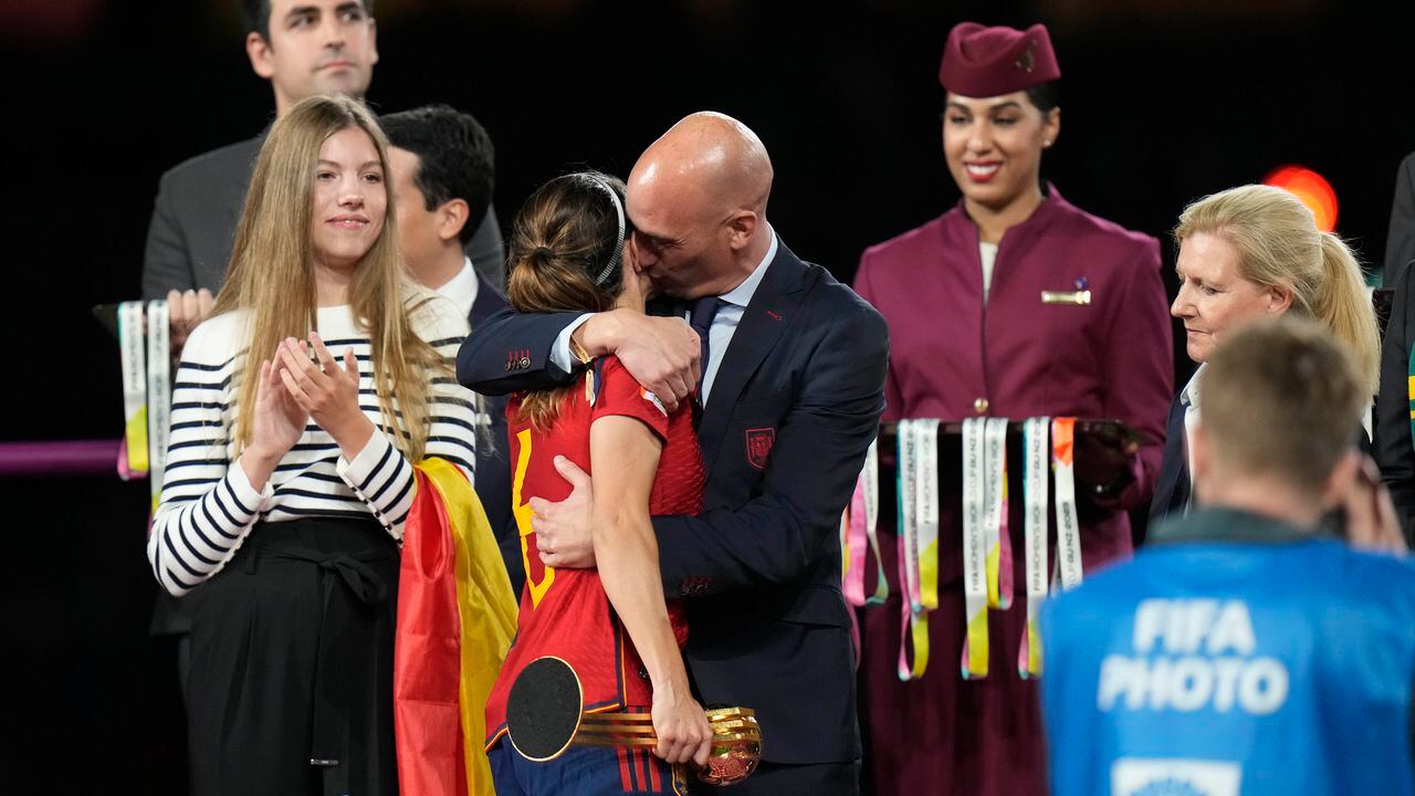El presidente de la federación española de fútbol, Luis Rubiales (derecha) abraza a la volante Aitana Bonmatí en el podio tras la victoria de España ante Inglaterra en la final del Mundial femenino, el domingo 20 de agosto de 2023, en Sidney. A la izquierda aparece la princesa Sofía. (Foto AP/Alessandra Tarantino)