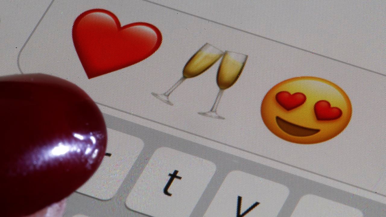 En esta ilustración fotográfica, un emoji o emoticón que representa un corazón, una copa de champán y ojos en forma de corazón se muestran en la pantalla de un iPhone