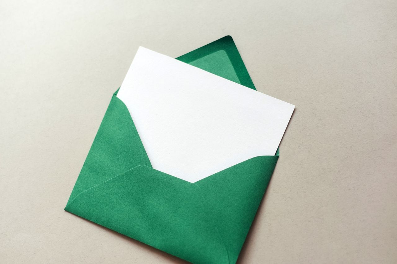 Green envelope with a white sheet on a gray background. Wish list. New Year. Christmas.