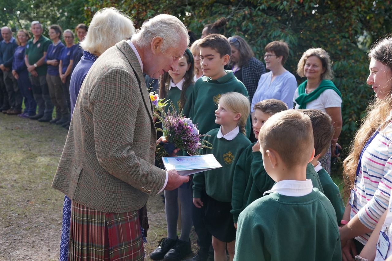 La reina Camilla de Gran Bretaña (L) y el rey Carlos III de Gran Bretaña (2L) reciben flores y una tarjeta de los niños de las escuelas locales cuando salen después de asistir a un servicio religioso en el pueblo de Crathie, cerca de Balmoral en el centro de Escocia, el 8 de septiembre de 2023, para conmemorar. la vida de la madre del rey, Su difunta Majestad la Reina Isabel II en el primer aniversario de su fallecimiento. El viernes 8 de septiembre se cumple en Gran Bretaña el primer aniversario de la muerte de la reina Isabel II, pero las conmemoraciones serán discretas y no se planean eventos públicos oficiales. (Foto de Andrew Milligan / PISCINA / AFP)