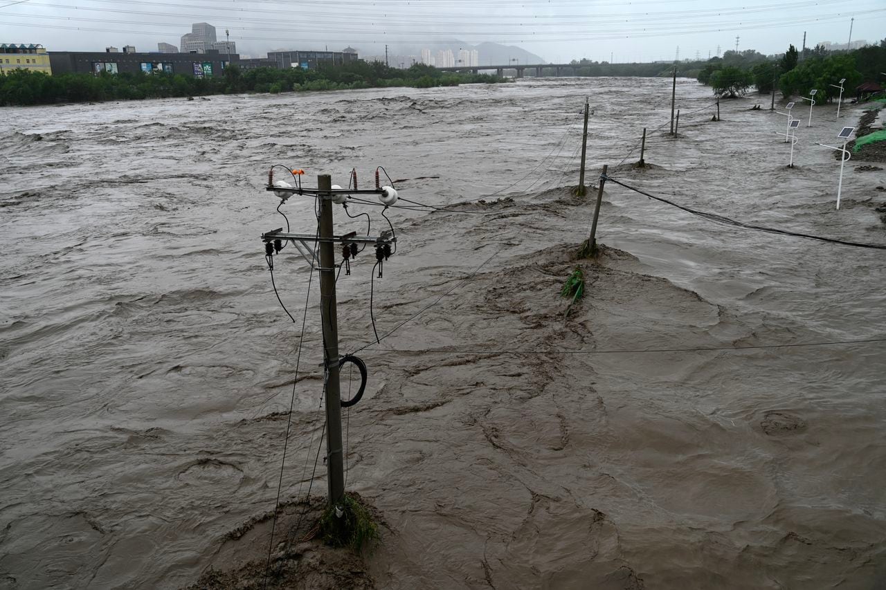 This picture shows a view of the overflooded Yongding river, after heavy rains in Mentougou district in Beijing on July 31, 2023. Heavy rains battered northern China on July 31, killing at least two people in Beijing while washing away cars and inundating subway stations, with the capital issuing its highest alerts for flooding and landslides. (Photo by Pedro PARDO / AFP)