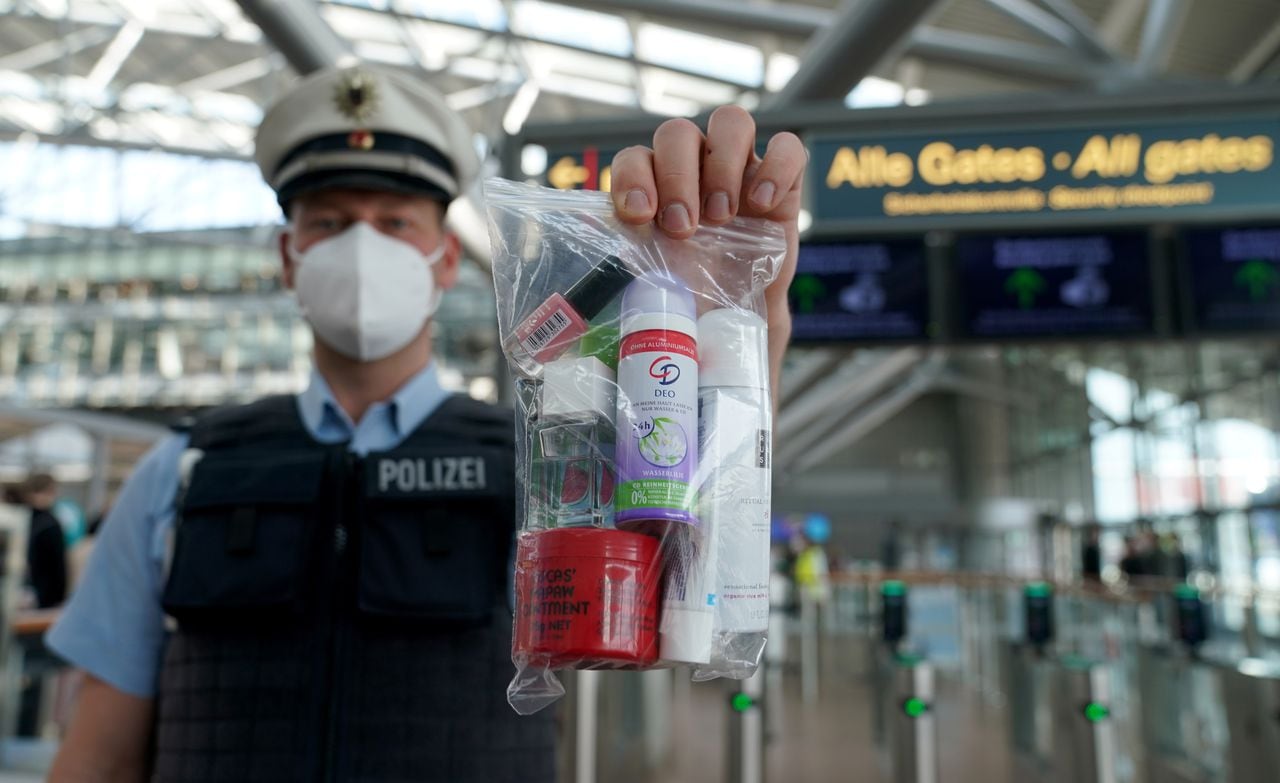 Un policía sostiene una bolsa con cerradura que contiene cosméticos que pueden llevarse en el equipaje de mano en un vuelo, fuera del control de seguridad del aeropuerto de Hamburgo.