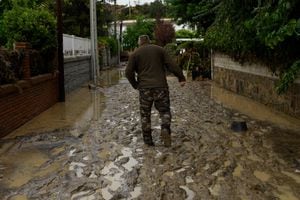 A resident walks in a flooded street in the town of Aldea del Fresno, in the Madrid region on September 4, 2023, as a man was reported missing after his vehicle was swept away by an overflowing river during heavy rains, according to Madrid's emergency services. Affected for months by a historic drought, Spain has been hit by torrential rain that left two people dead and three missing on September 4. This meteorological phenomenon, known as the "Dana" ("isolated high-level depression" in Spanish), began on September 3 afternoon and continued into the night, particularly in Madrid and Castilla-La-Mancha, where torrents of water poured down. (Photo by Oscar DEL POZO CA�AS / AFP)