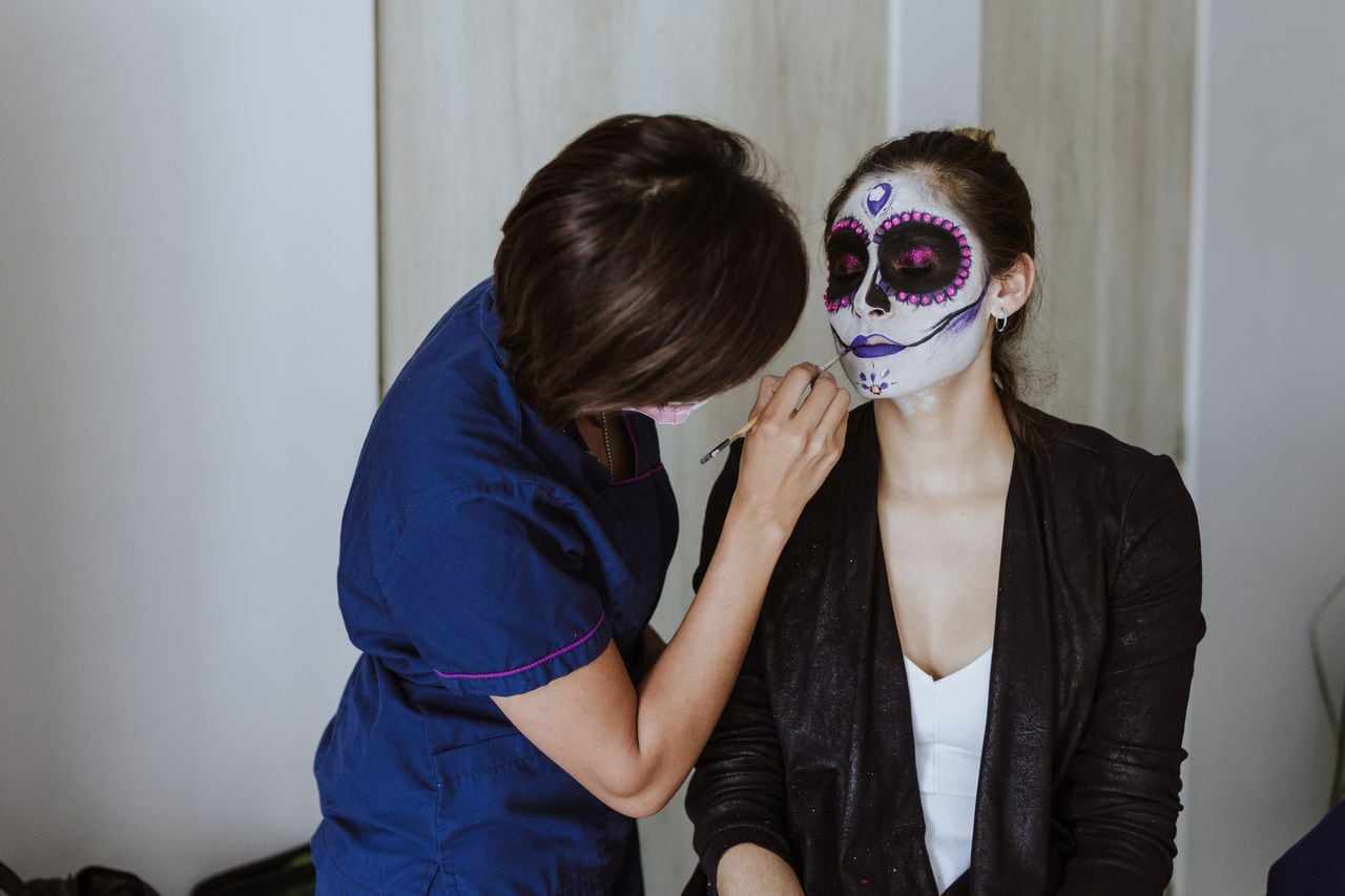 mexican Catrina, young latin woman makeup artist making a traditional skeleton for Day of the Dead or Halloween in Mexico