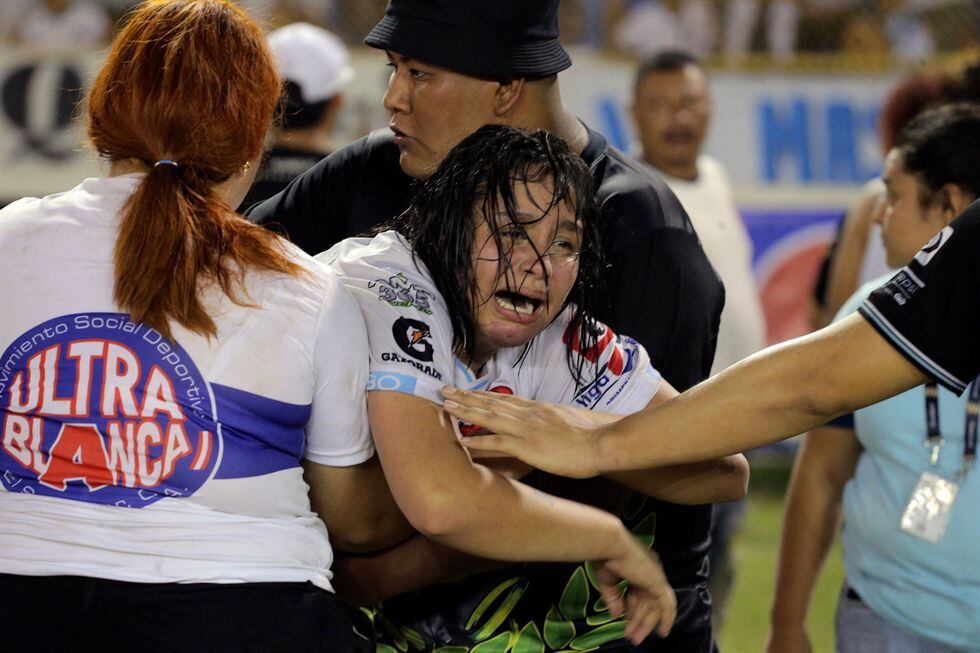 Una mujer es sostenida por otra mientras llora luego de una estampida durante un partido de fútbol entre Alianza y FAS en el estadio Cuscatlán en San Salvador.