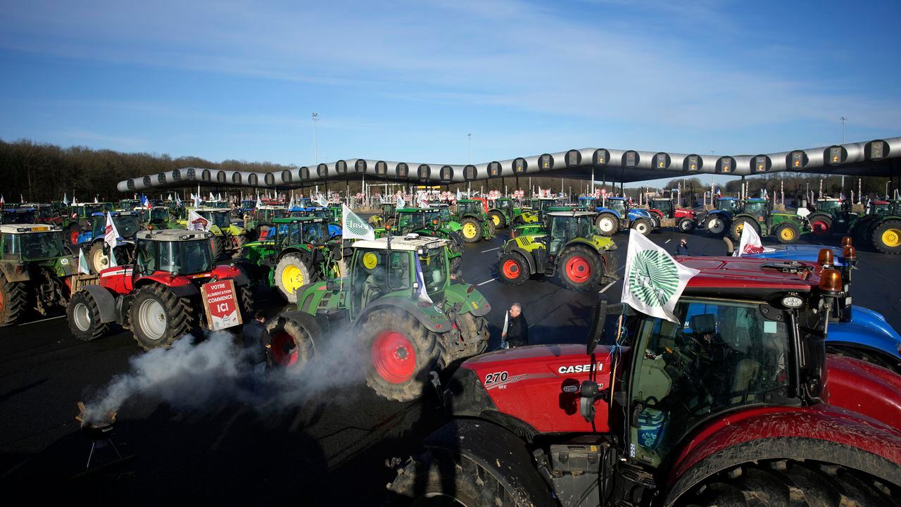Los agricultores bloquean el peaje de la autopista Saint-Arnoult con sus tractores, el viernes 26 de enero de 2024 en Saint-Arnoult, al sur de París. Los agricultores que protestaban cerraron largos tramos de algunas de las principales autopistas de Francia el viernes, utilizando sus tractores para bloquear y ralentizar el tráfico y presionar cada vez más al gobierno para que ceda a sus demandas de que el cultivo y la cría de alimentos deberían ser más fáciles y lucrativos.