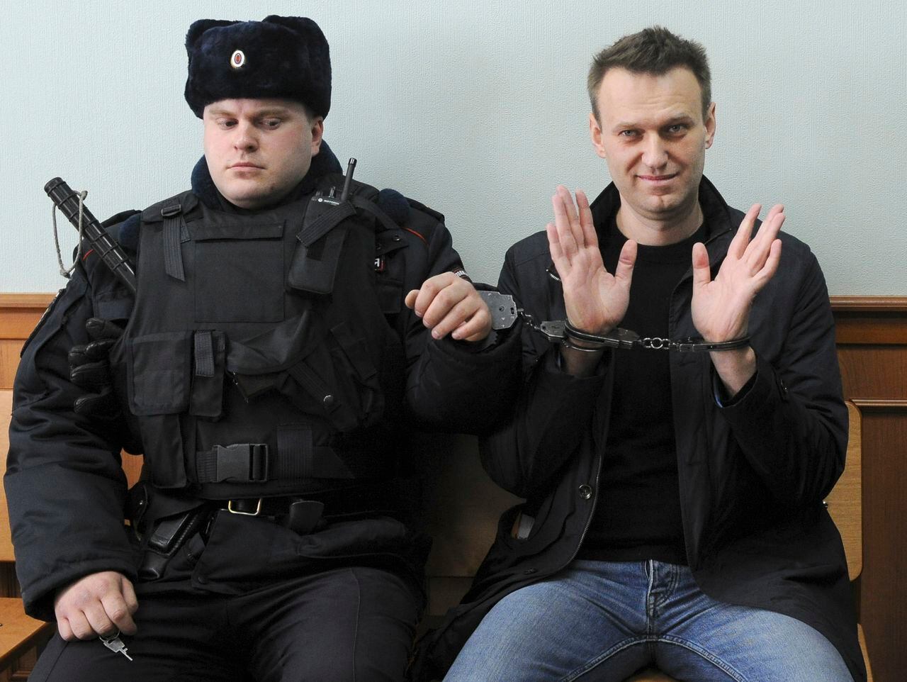 El líder de la oposición rusa Alexei Navalny, derecha, posa para la prensa mientras está sentado esposado en un tribunal en Moscú, Rusia, el 30 de marzo de 2017. La agencia penitenciaria de Rusia dice que el líder de la oposición encarcelado Alexei Navalny ha muerto.