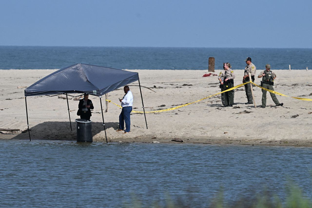Officials stand next to a barrel where a body was discovered in Malibu Lagoon State Beach, California on July 31, 2023. A body stuffed in a barrel was discovered July 31, 2023 on Malibu Beach, a swanky Californian hotspot beloved by the rich and famous, police said. Reports said the man's corpse was crammed into a 55-gallon drum when it was discovered by maintenance workers. (Photo by Robyn Beck / AFP)