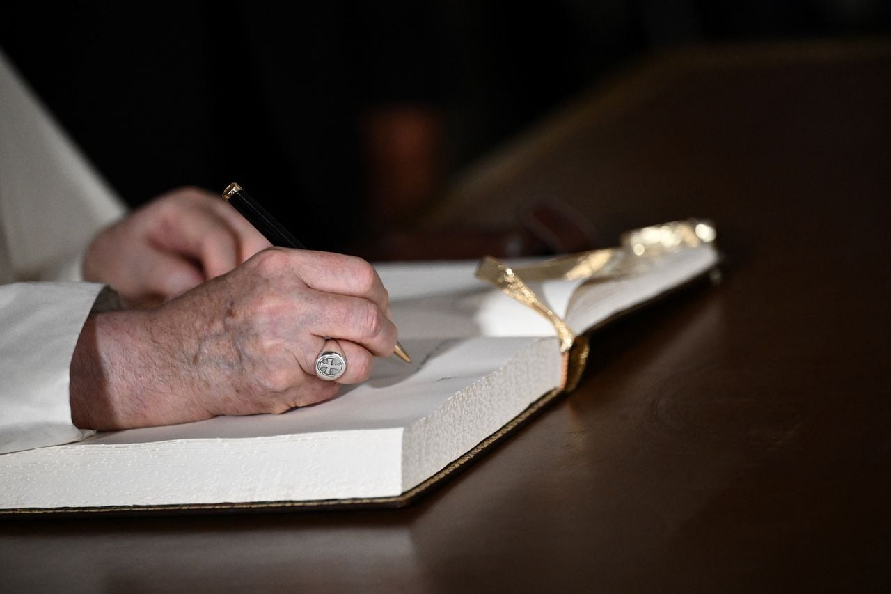 Pope Francis signs a guestbook at the National Palace in Belem, Lisbon, during his five-day visit to attend the World Youth Day (WYD) gathering of young Catholics, on August 2, 2023. Pope Francis arrived in Lisbon today to gather with a million youngsters from across the world at the World Youth Day (WYD), held as the Church reflects on its future. The 86-year-old underwent major abdominal surgery just two months ago, but that has not stopped an event-packed 42nd trip abroad, with 11 speeches and around 20 meetings scheduled. (Photo by Marco BERTORELLO / AFP)