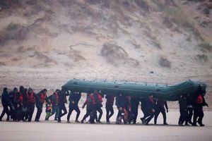 Un grupo de más de 40 migrantes corre por la playa con un bote inflable, para dejar la costa del norte de Francia y cruzar el Canal de la Mancha, cerca de Wimereux, Francia, el 24 de noviembre de 2021. Foto REUTERS / Gonzalo Fuentes TPX IMÁGENES DEL DÍA