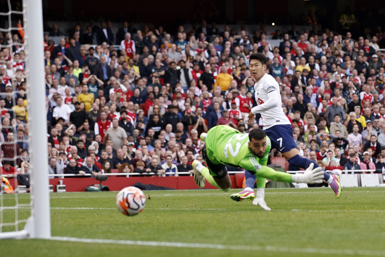 Son Heung-min del Tottenham anota el segundo gol de su equipo superando al portero del Arsenal David Raya durante el partido de fútbol de la Liga Premier inglesa entre Arsenal y Tottenham Hotspur en el estadio Emirates de Londres, Inglaterra, el domingo 24 de septiembre de 2023. (Foto AP/David Cliff)