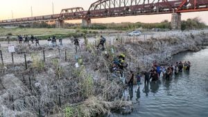 Las personas que cruzaron la frontera entre Estados Unidos y México buscan un paso a través de alambre de púas en el lado texano del Río Grande.
