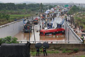 Los rescatistas de Corea del Sur buscan personas desaparecidas cerca de un autobús a lo largo de una carretera inundada que conduce a un túnel subterráneo donde unos 15 automóviles quedaron atrapados en las aguas de la inundación después de las fuertes lluvias en Cheongju el 16 de julio de 2023.