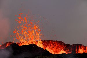People watch flowing lava during an volcanic eruption near Litli Hrutur, south-west of Reykjavik in Iceland on July 10, 2023. A volcanic eruption started on July 10, 2023 around 30 kilometres (19 miles) from Iceland's capital Reykjavik, the country's meteorological office said, marking the third time in two years that lava has gushed out in the area. "The eruption is taking place in a small depression just north of Litli Hrutur, from which smoke is escaping in a north-westerly direction," the office said. Footage circulating in the local media shows a massive cloud of smoke rising from the ground as well as a substantial flow of lava. (Photo by Kristinn Magnusson / AFP) / Iceland OUT