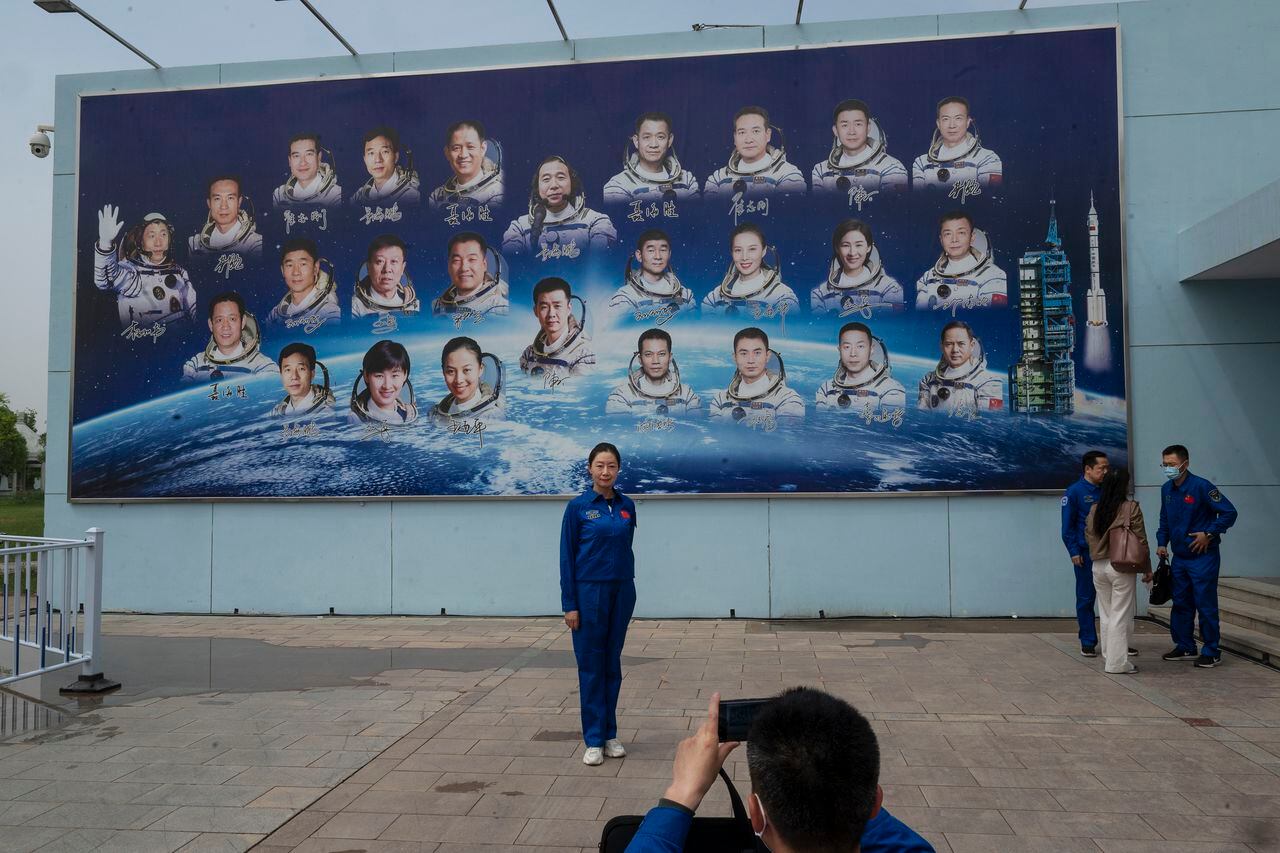 Un empleado de la Agencia Espacial Tripulada de China toma fotos frente a un tablero que muestra a los astronautas del país después de una conferencia de prensa previa al lanzamiento de la misión Shenzhou-16 en el Centro de Lanzamiento de Satélites de Jiuquan