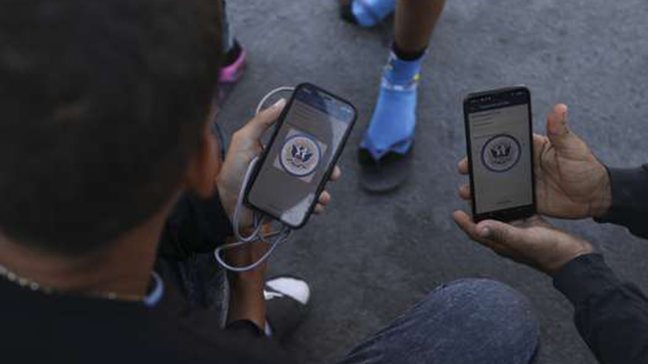 Migrantes venezolanos navegan por la aplicación móvil CBP One en busca de una cita para ingresar a Estados Unidos fuera de la estancia temporal del Instituto Nacional de Migración (INM) en Ciudad Juárez, estado de Chihuahua, México