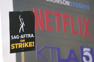 A picketer carries a sign on the picket line outside Netflix on Wednesday, Sept. 27, 2023, in Los Angeles. Hollywood's writers strike was declared over Tuesday night when board members from their union approved a contract agreement with studios, bringing the industry at least partly back from a historic halt in production. The actors strike continues in their bid to get better pay and working conditions. (AP Photo/Chris Pizzello)