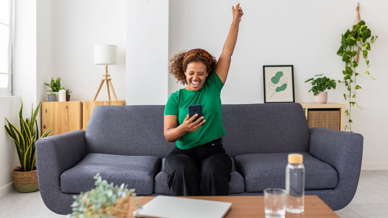 Excited young african woman celebrating success looking mobile phone screen
