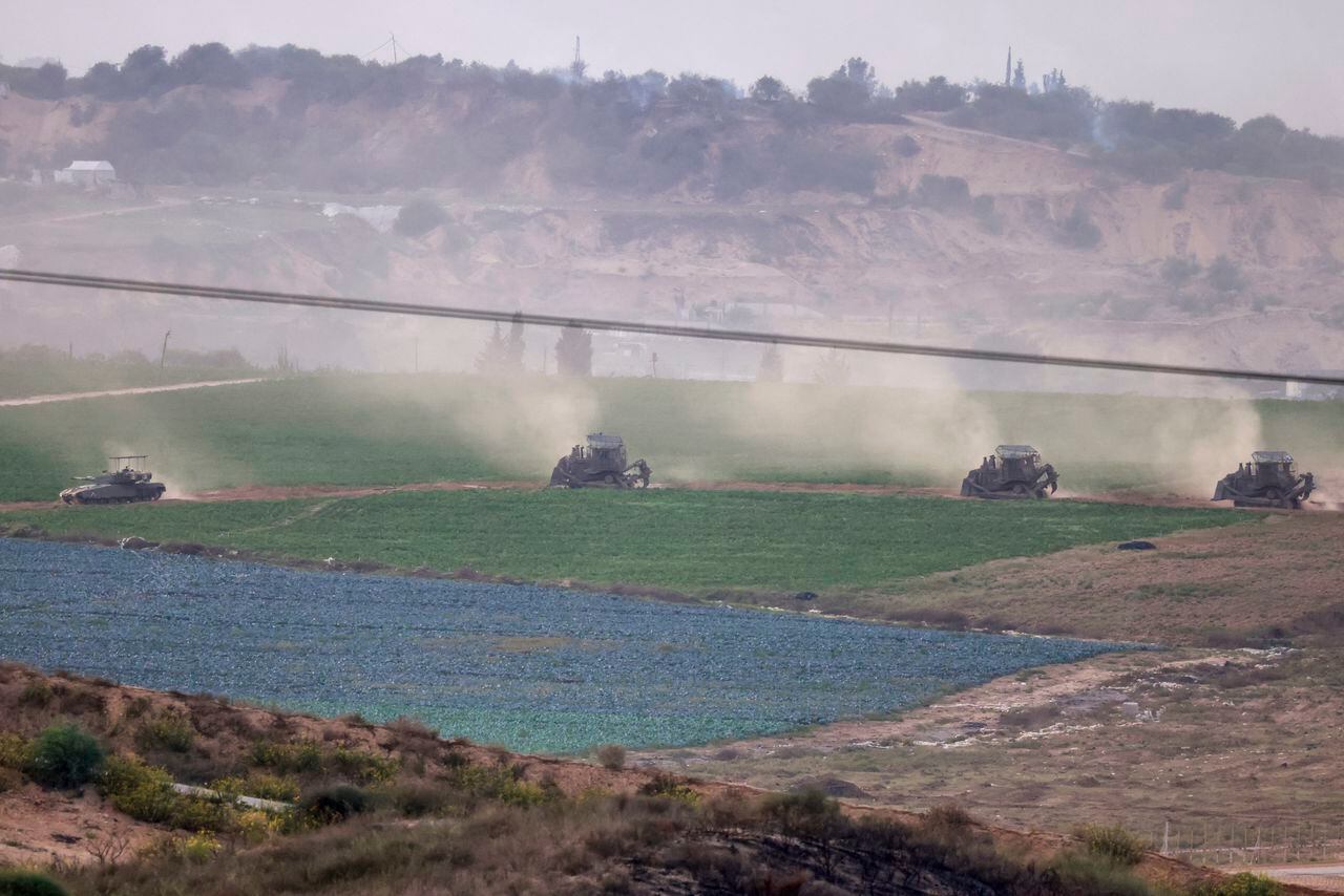 Una fotografía tomada desde el sur de Israel a lo largo de la frontera con la Franja de Gaza muestra excavadoras y tanques del ejército israelí cruzando la frontera hacia Gaza, el 29 de octubre de 2023, en medio de batallas en curso entre Israel y el grupo militante palestino Hamás. (Photo by Menahem KAHANA / AFP)