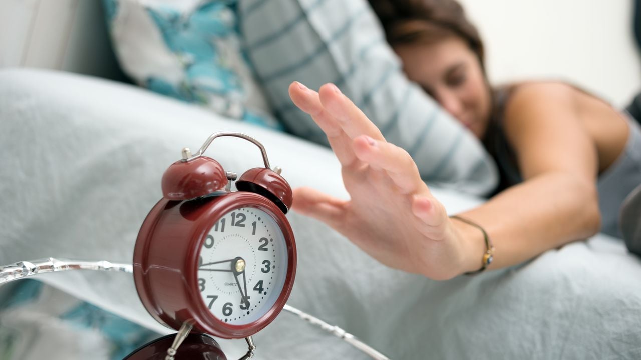 Mujer despertando con reloj despertador