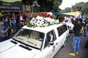 Aficionados del equipo de fútbol paraguayo Guaraní rinden homenaje al fiscal antidrogas Marcelo Pecci, quien también era hincha y miembro de la junta directiva, al pasar el coche fúnebre con su féretro antes de su funeral, en Asunción el 15 de mayo de 2022.