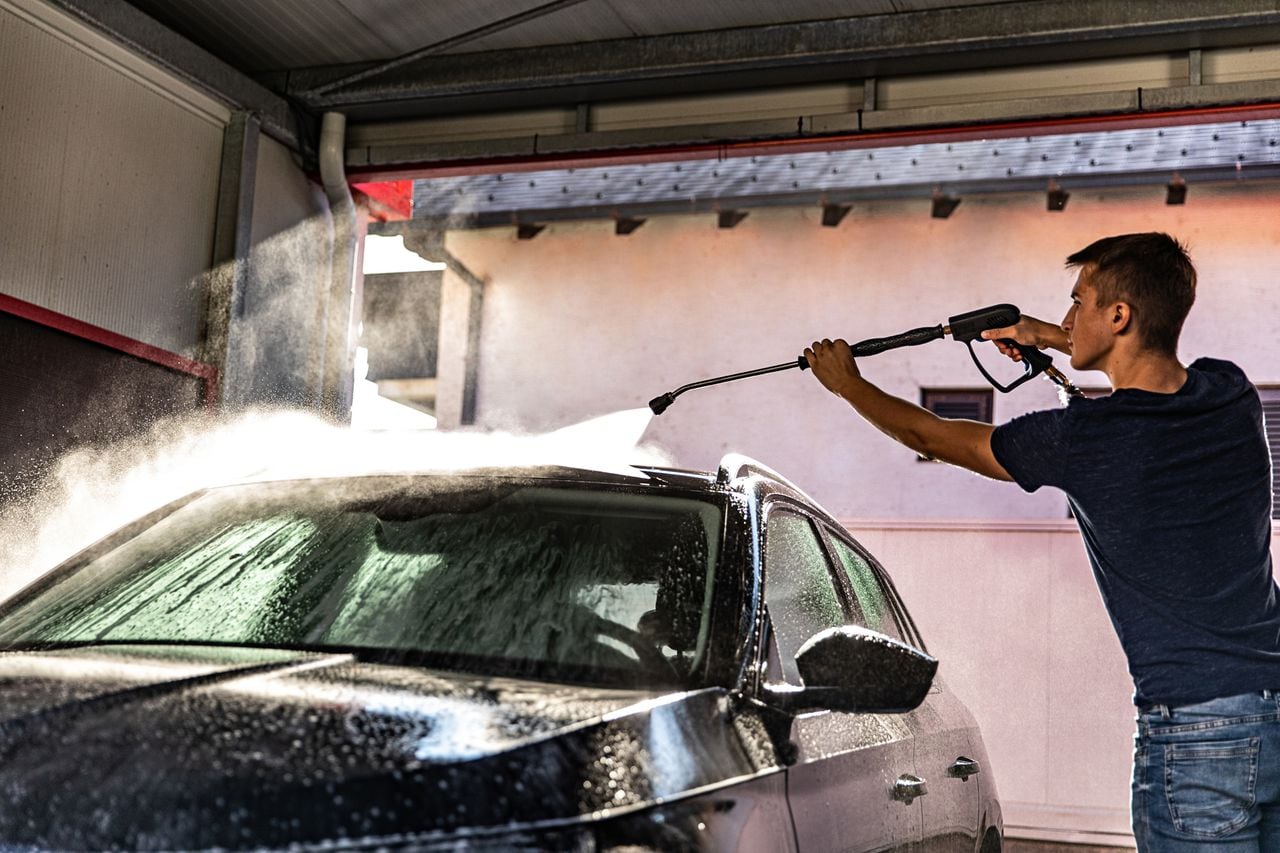 Young man spray washing black car
