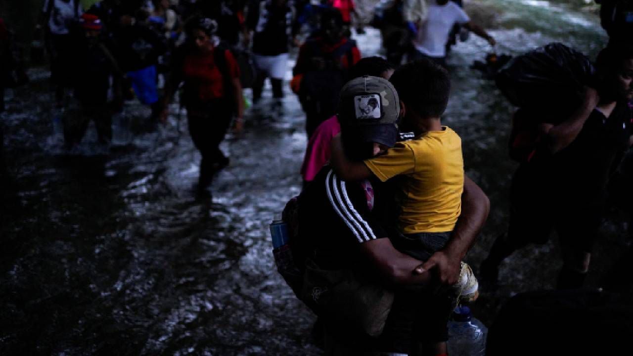 Un migrante venezolano lleva a su hijo mientras cruza el Tapón del Darién.