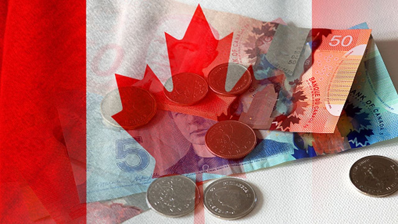 Billetes y monedas en efectivo en dólares canadienses y bandera de Canadá (dinero, economía, negocios, finanzas, inflación, crisis)