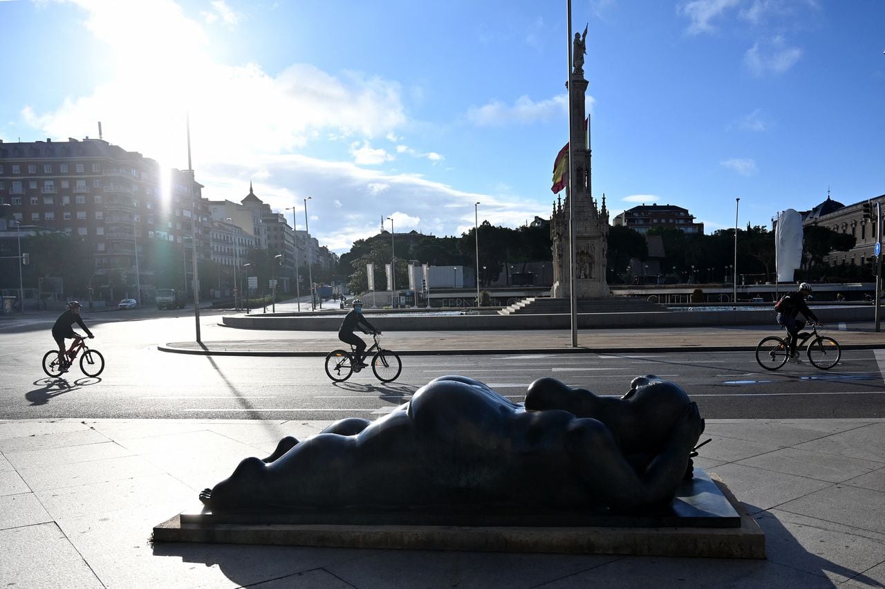 Los ciclistas pasan en bicicleta junto a la escultura "Mujer con espejo" del artista colombiano Fernando Botero en Madrid el 10 de mayo de 2020.
