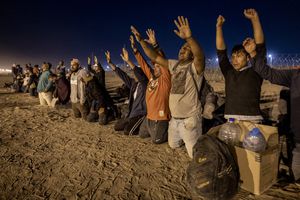 Inmigrantes rezan mientras esperan ser procesados por agentes fronterizos de EE. UU. para solicitar asilo después de cruzar desde México el 9 de mayo de 2023 en El Paso, Texas.