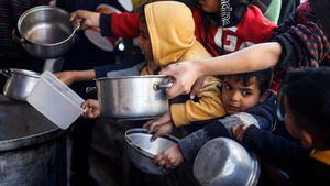 Niños palestinos esperan recibir comida cocinada en una cocina benéfica en medio de escasez de alimentos, mientras continúa el conflicto entre Israel y el grupo islamista palestino Hamás, en Rafah, en el sur de la Franja de Gaza, el 5 de marzo de 2024.