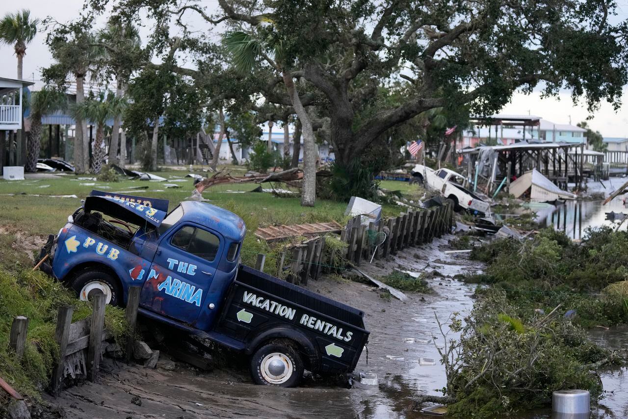 Camionetas y escombros obstruyen el flujo de las aguas de un canal en Horseshoe Beach, Florida, tras el paso de Idalia ya como huracán, el miércoles 30 de agosto de 2023. (AP Foto/Rebecca Blackwell)