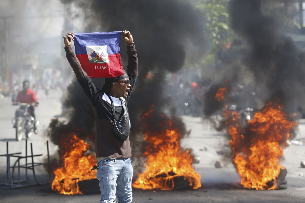 Un manifestante sostiene una bandera de Haití durante una protesta para exigir la renuncia del primer ministro Ariel Henry, el viernes 1 de marzo de 2024, en Puerto Príncipe. (AP Foto/Odelyn Joseph)